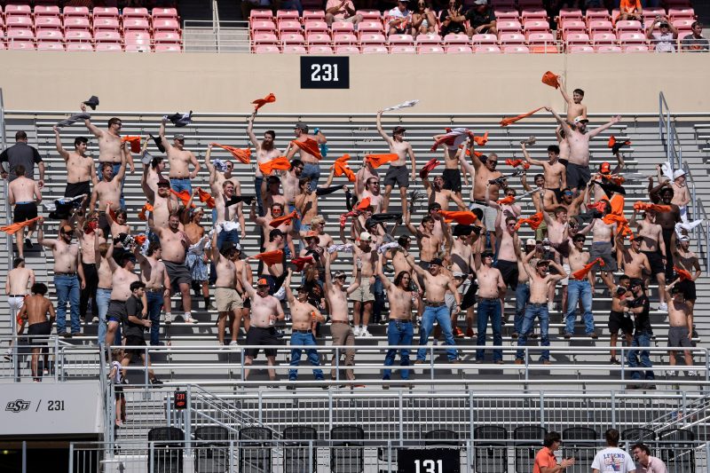 AI-assisted summary
A trend of fans taking off their shirts and waving them in the air has spread across college football.
The movement began when an Oklahoma State fan was dared by his sister to wave his shirt in an empty section of the stadium.
The trend has served as reminder for people to have fun at college football games, regardless of the result.
Viruses are terrifying. Once it finds a host, it can spread rapidly and infecting all victims anywhere in its path. 
There’s a new virus spreading through college football. In just a few weeks, it’s gone from one stadium to stretching across the country, contaminating nearly every cathedral that houses the sport. The symptoms?
Fans taking off their shirts and waving them in the air in the masses. 
Like most infectious diseases, it can be traced to a starting point. A dare between siblings on Oct. 11 in Stillwater, Oklahoma, led to its birth. In a matter of weeks, it’s taken over college football to produce one of the most mesmerizing sights to behold.  
“It’s not what you expected to happen,” Trent Eaton told USA TODAY Sports.
Is it really an illness? No, even if it appears to be making people mad. 
Is it bad? Far from it, as it has reminded those that started it what college football is all about: having fun. 
How viral Oklahoma State trend began
It’s no secret 2025 has been a bad one for Oklahoma State. Entering that Oct. 11 afternoon, the Cowboys were 1-4 and had fired longtime coach Mike Gundy. Oklahoma State student Luke Schneberger recalled the vibes inside Boone Pickens Stadium “were just not there.”
Through three quarters against Houston, the Cowboys were down 36-10 and headed toward a fifth consecutive loss. The stadium was emptying when Eaton, a lifelong Cowboys fan, was dared by his sister Callista Bradford, a season ticket holder, to go to a lifeless section, take off his shirt and wave it for $10. 
Not ashamed, Eaton walked around the stadium to section 231 and by himself, waved his shirt for the crowd to see. Patient No. 0. 
It takes more than one for a virus to thrive. Luckily, Schneberger’s friends saw Eaton on the jumbotron. They said he should go join him. Schneberger thought it was a good idea.
So, Schneberger walked up to section 231. He and Eaton didn’t know each other, but only a few words were said to connect them.
“Hey man. Mind if I join you?” Schneberger said.
“Yeah, c’mon,” Eaton responded.
Patient No. 1. The two strangers stood together, laughing and waving their shirts as the sun beamed on their torsos. While attempting to boost the mood, neither weren’t sure how long they would last. 
Call it dramatic or silly, but it can get pretty tiring swinging your arm. Eaton said he had enough juice until the end of the third quarter, while Schneberger didn’t know how long he could go.
That’s when a group of guys walked by and Schneberger encouraged them to join. They did, and the group grew.
Before they realized it, the entire section and nearby ones were filled with guys enthusiastically waving their shirts. 
“I didn’t expect as many people as ended up coming up to happen,” Eaton said.
Call it an outbreak. 
The scene went viral as Oklahoma State and college football fans watched in amazement of the “tarps off” scene. There is no real way to describe it other than just guys being dudes. 
“If you looked up guys being dudes in the dictionary, the tarps off sections would probably be in there,” Schneberger said.
Waving shirts spread
Eaton became an instant celebrity in Stillwater, taking photos with admirers when he and his sister went to get food after the game. While it was a cool moment that brought joy to a miserable fan base, Eaton and Bradford figured it would be a one game thing.
That was until later in the week when someone sent Bradford a video from a local high school volleyball game, where a group of boys replicated her brother.
The movement spread out of Boone Pickens Stadium. Next thing they knew, it found its way to other college football stadiums. One week later, it was done at Wisconsin’s Camp Randall Stadium. Also at the Rose Bowl for UCLA’s home game. 
A week later, the virus continued to grow to Virginia Tech, North Carolina and several others. It even made its way to Eugene, Oregon, where even the Oregon Duck mascot did it. Section 231 at Oklahoma State became known as 2-no shirty-1.
“I saw videos all across the states of several college teams doing it,” Bradford said. “I was like, ‘oh man, we started a trend.’”
Why has shirtless movement become popular?
Other than believing it’s some viral infection, there’s no way to explain why this trend has caught on.
“It was just shocking to me how fast it spread,” Schneberger said. “Something that I was a small part in getting that big is just very surreal for me.”
Eaton wasn’t the first person to ever wave their shirt at a sporting event, but it has clearly resonated. He pointed to where this movement took shape. Oklahoma State is in the midst of a struggling season. So are UCLA, Wisconsin and North Carolina. It became a big thing by the time it caught on to good teams like Oregon.
“Most fans realize that their team’s not always going to be great, but they can still go support them and have fun and make something out of not a great season,” Eaton said. 
Schneberger agreed, adding that fans can’t just feel down the entire time and make some fun in even the worst situations. Even though Oklahoma State lost that Houston game by 22 points, it brought some joy to campus. Bradford also noted going to games is about more than the result; the atmosphere and fun are what makes the experience so unique.
“It’s that perfect recipe for it to be for college football,” Schneberger said. “It’s such a fun thing to do. Just get up there with your buddies and, you know, swing your shirt around.”
There’s no telling how long this virus will last. Eaton and Bradford have both been invited back for Oklahoma State’s next home game on Nov. 15 to be recognized, where the shirtless fun can very well continue in Stillwater. We will also have to see if the virus can survive the winter conditions that are on the horizon for the rest of the country.
“You’re not always on top,” Bradford said. “But you can also always have a good time.”
This post appeared first on USA TODAY